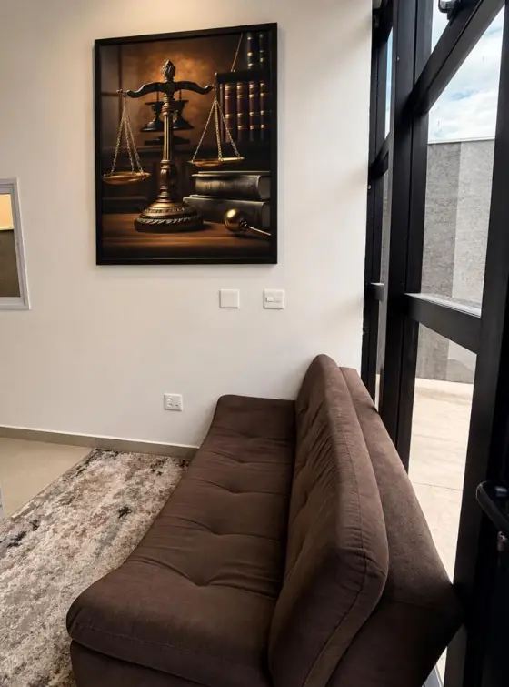 Sala de espera da recepção com sofá e quadro da balança da Justiça